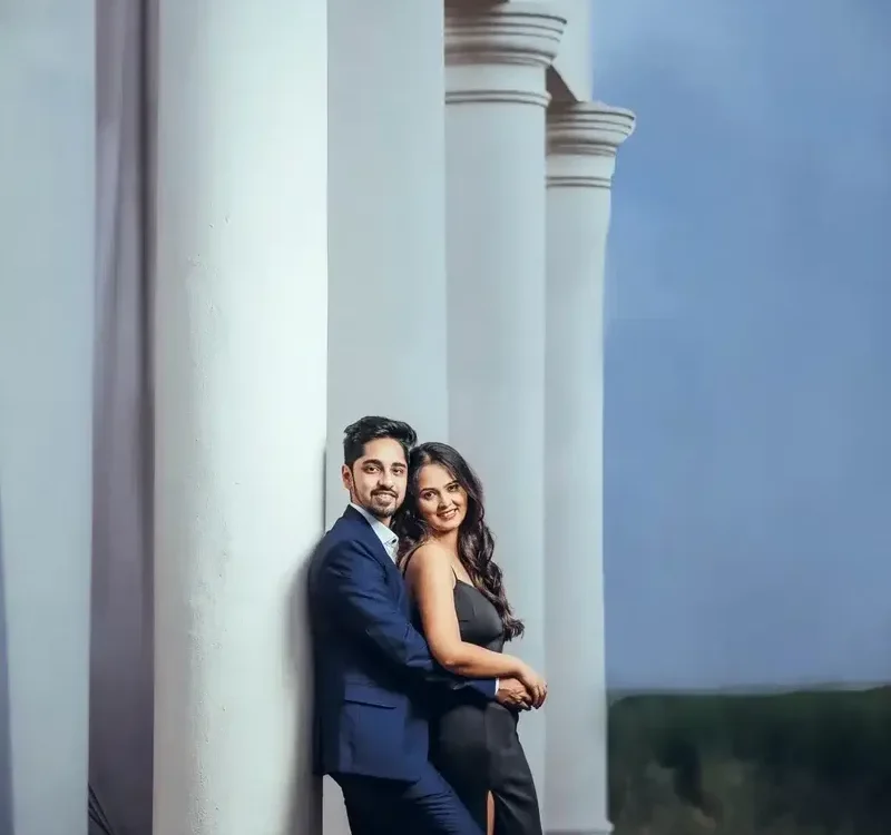 Couple in formal outfits during pre wedding shoot planning at a white pillar location