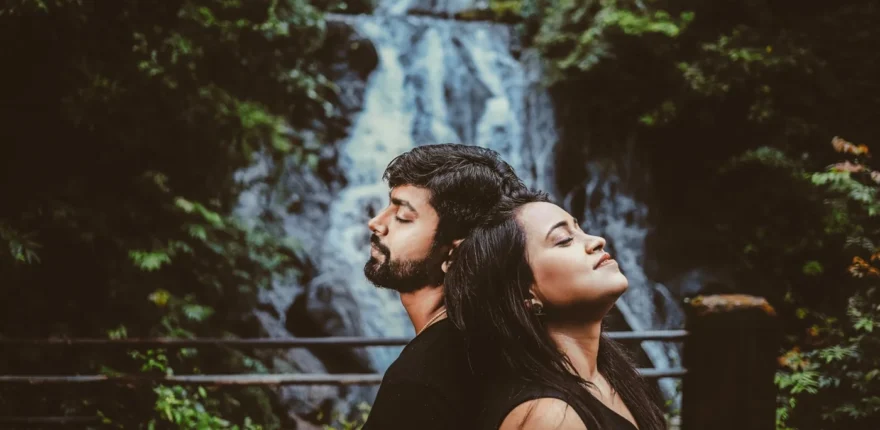 Best time for pre wedding shoot in Indore Indian couple standing close with eyes closed in front of a forest waterfall during a soft-light pre-wedding shoot near Indore