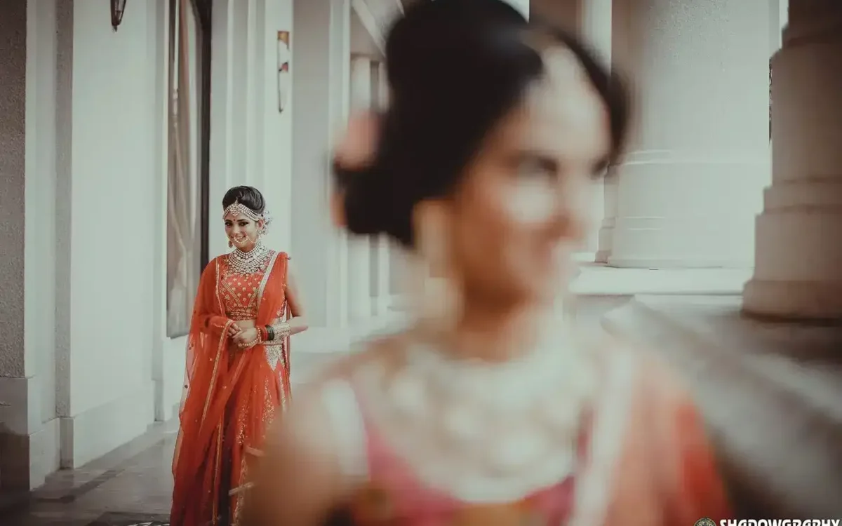 Bride in a red lehenga reflected in a mirror, bridal portrait by Wedding Photographer in Indore - WPI