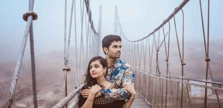 Must-have wedding photos guide - couple portrait Couple embracing on a misty suspension bridge, the man in a floral shirt with his arms around the woman