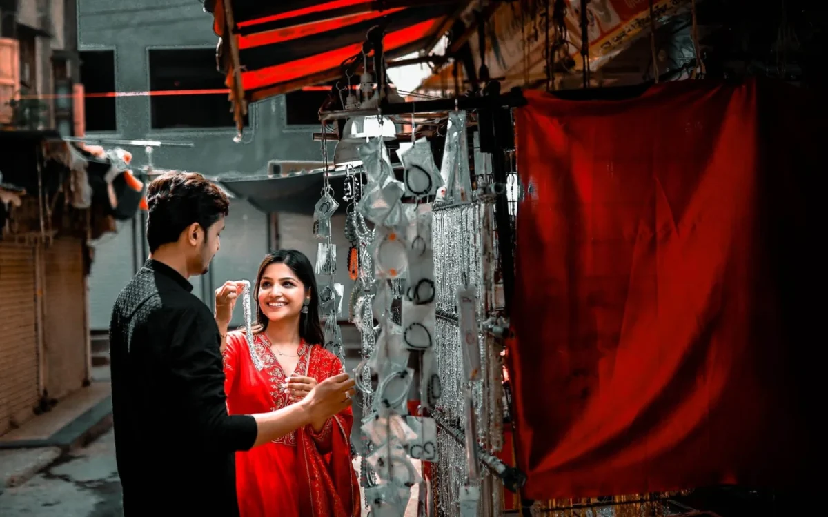 Couple in black and red outfits smiling beside a jewellery stall beneath a red awning