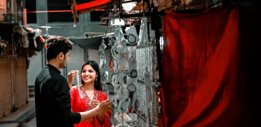 Couple in black and red outfits smiling beside a jewellery stall beneath a red awning