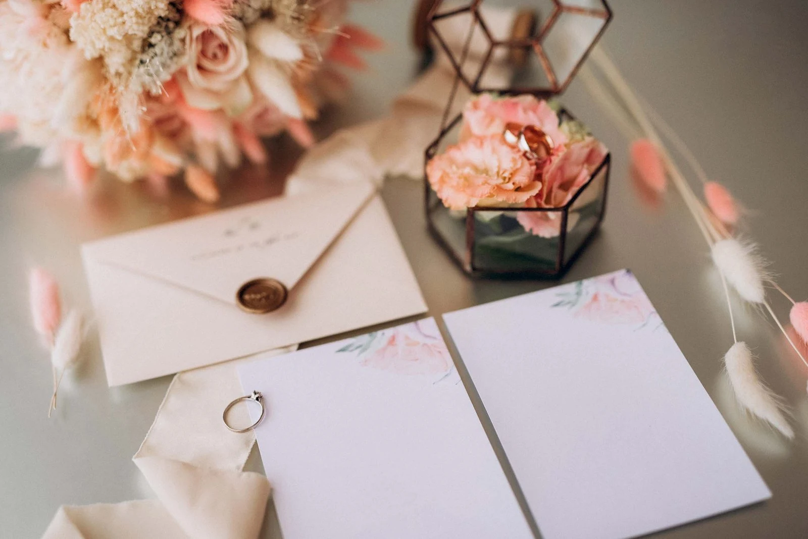 Wedding rings, invitation cards and flowers arranged on a table