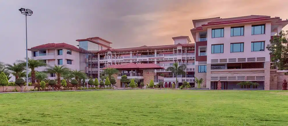 A pink resort building with a wide green lawn in front