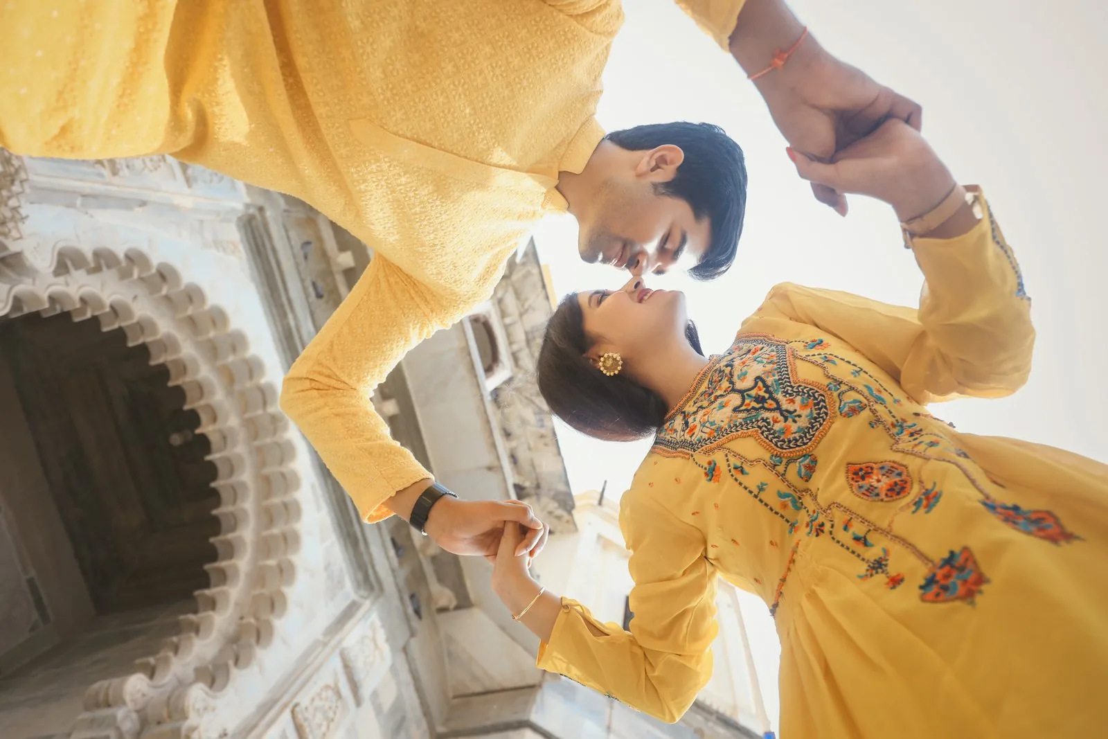 Couple in yellow outfits holding hands during a close portrait