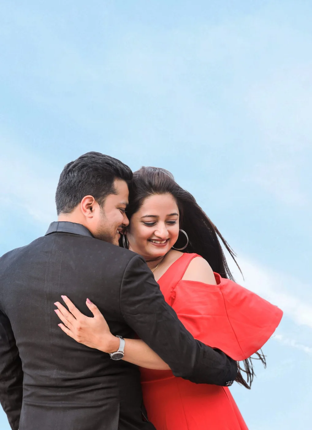 Couple laughing against a blue sky - wedding photography style that fits their personality