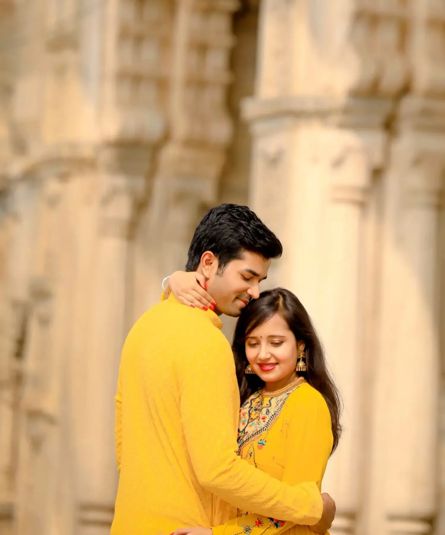 Couple in yellow outfits at heritage pillars during their wedding planning timeline