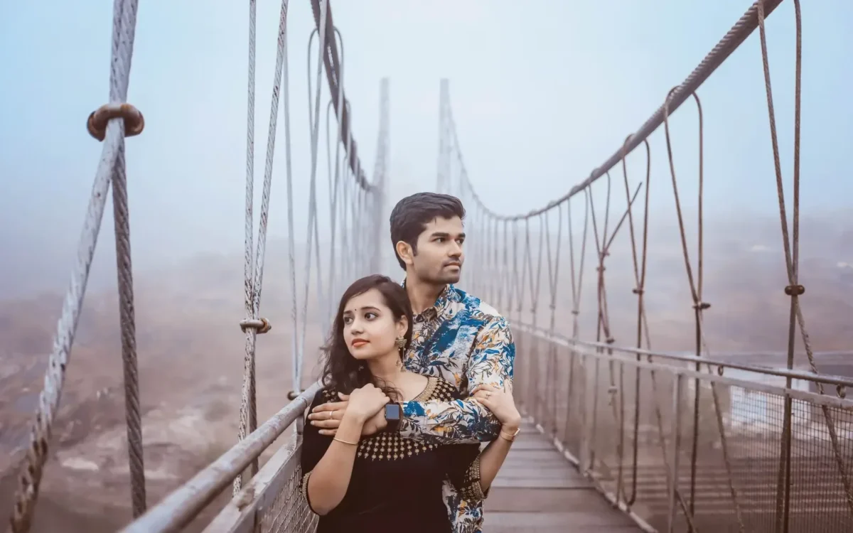 Couple embracing on a misty suspension bridge during an outdoor portrait session