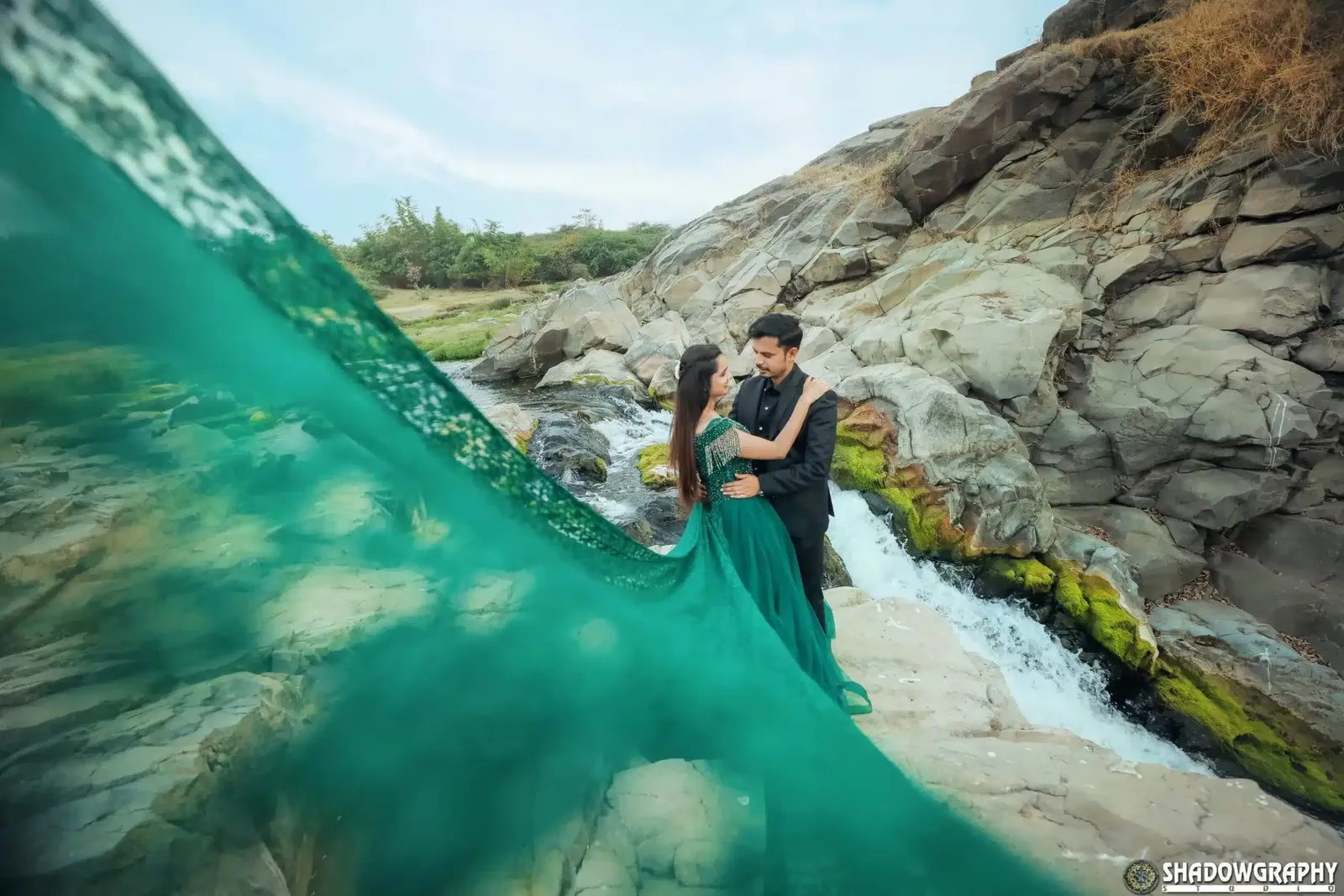 Couple with flowing gown in a waterfall setting, cinematic pre-wedding photography