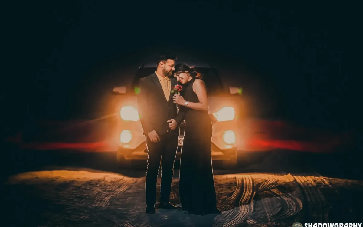 Couple standing in front of car headlights at night for a pre-wedding shoot