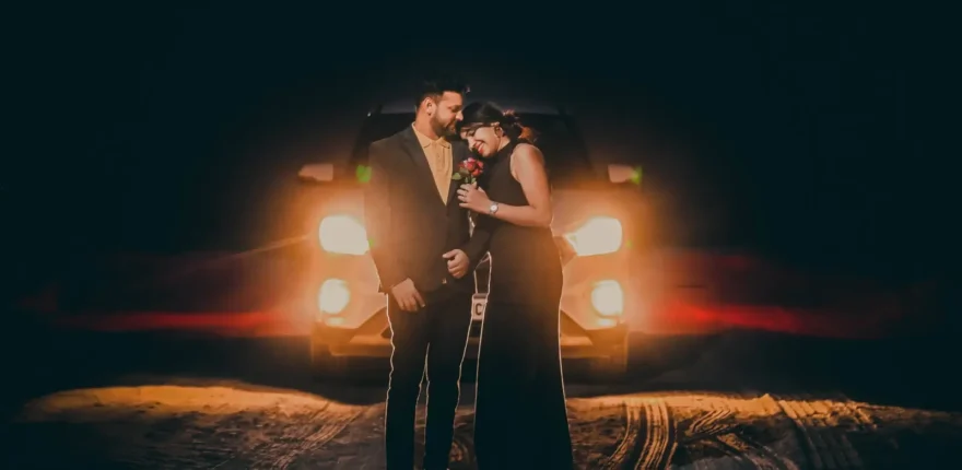 Couple standing in front of car headlights at night for a pre-wedding shoot