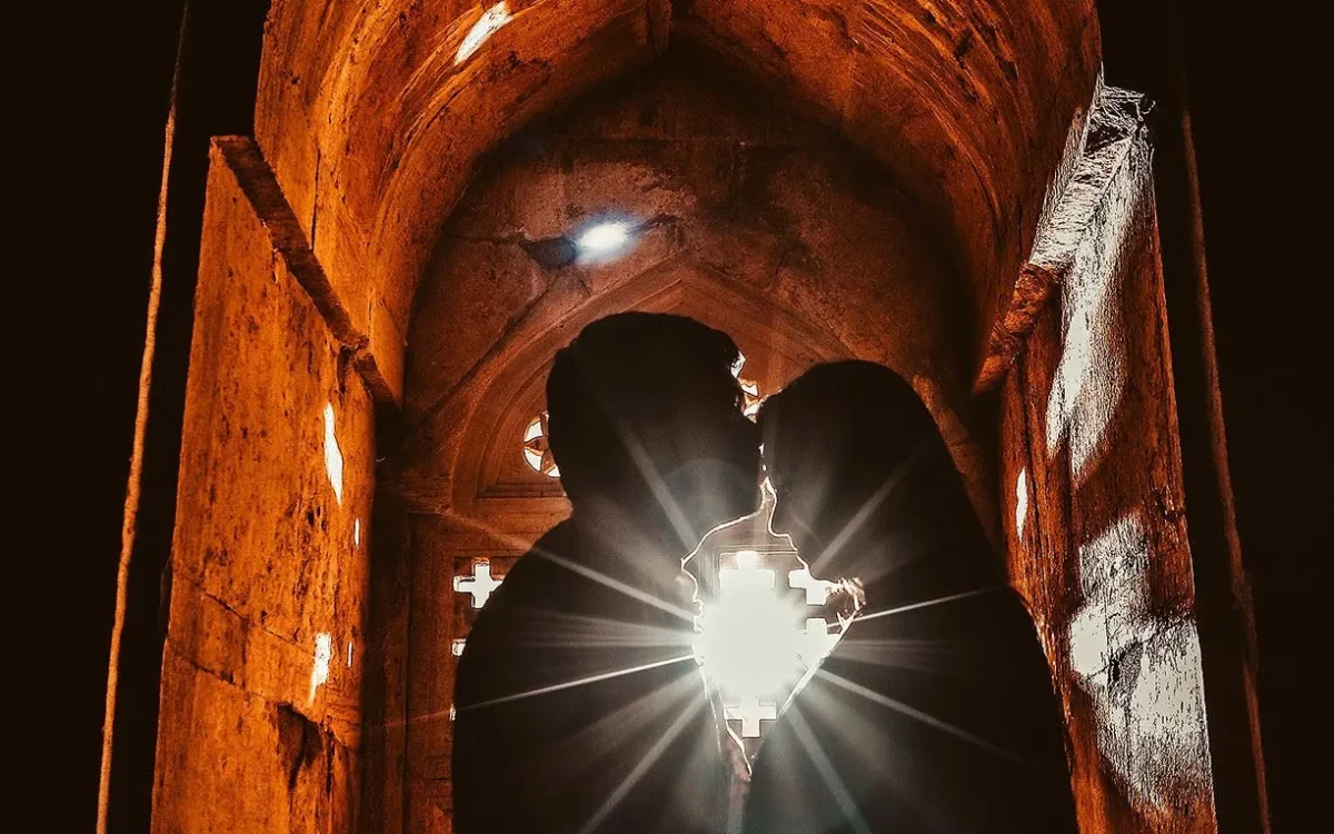 Silhouette of a couple kissing in a glowing heritage archway, pre-wedding shoot