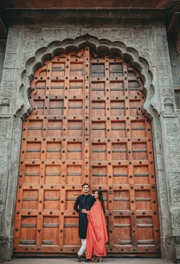 Pre-wedding couple beside a carved wooden door at Rajwada in Indore