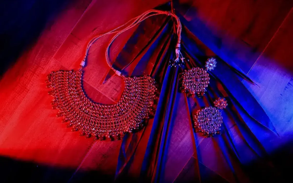 Bridal necklace and earrings laid out in rich red and blue light, wedding jewellery detail photograph