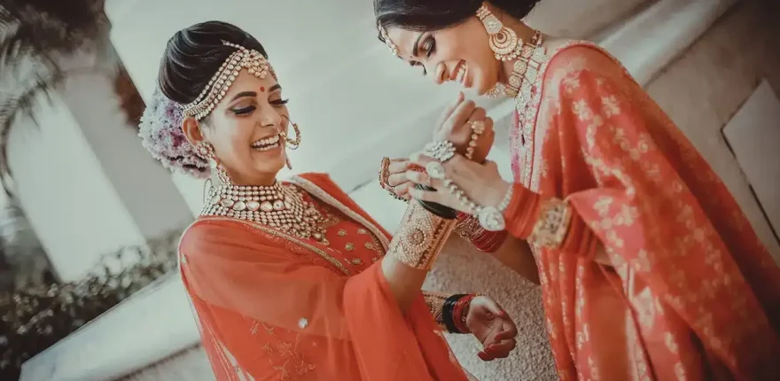 Two women laughing as a bride gets ready, candid wedding photography in Indore