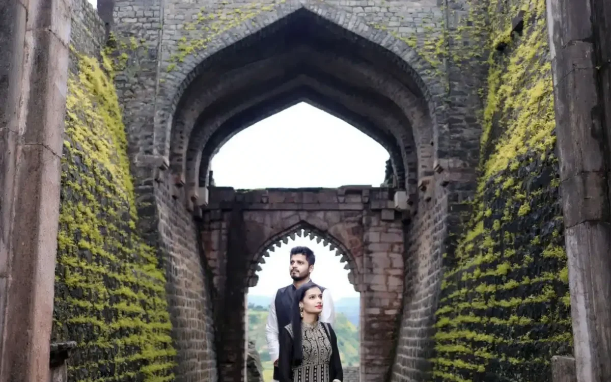 Couple standing together under a carved stone archway at a heritage monument in Mandu